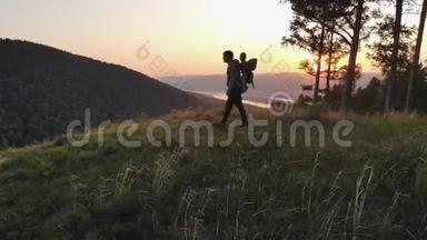 一个人和他的孩子一起旅行。 父亲给儿子看<strong>站在山顶</strong>上的日落。